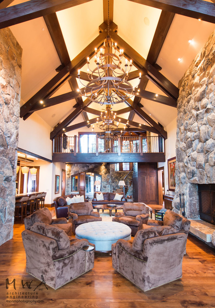 Expansive traditional open plan games room in Other with beige walls, dark hardwood flooring, a standard fireplace, a stone fireplace surround, a concealed tv and grey floors.