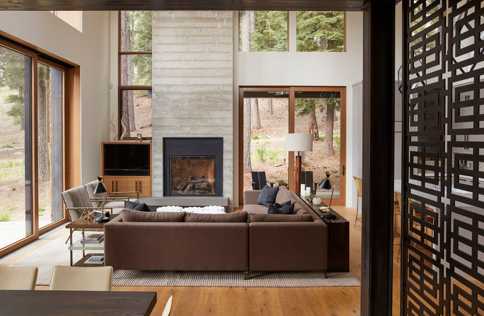 Cette image montre une salle de séjour design de taille moyenne et ouverte avec un mur beige, un sol en bois brun, une cheminée standard, un manteau de cheminée en béton, un téléviseur encastré et un sol marron.