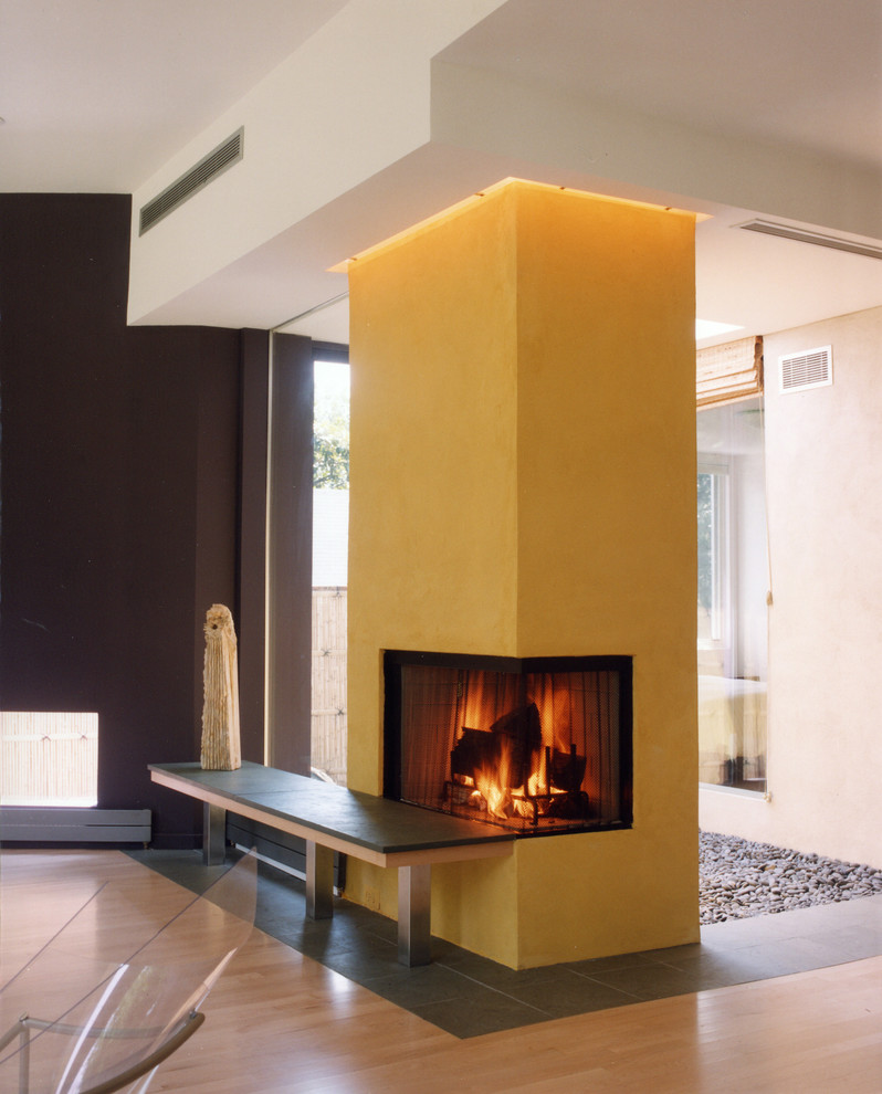 Diseño de sala de estar abierta minimalista de tamaño medio sin televisor con suelo de madera clara, chimenea de doble cara, marco de chimenea de yeso y paredes multicolor