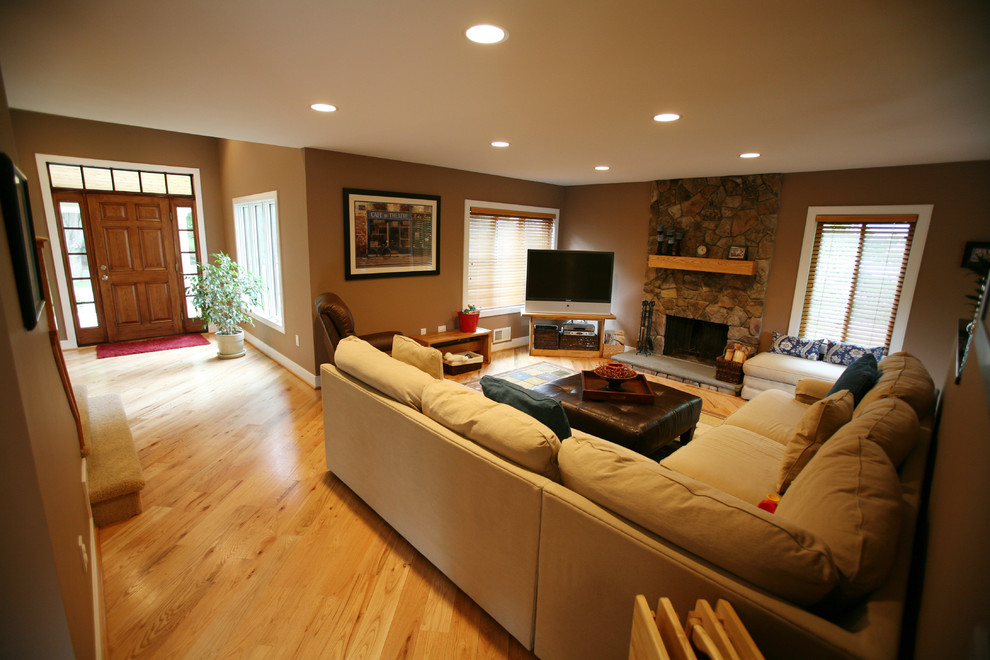Источник вдохновения для домашнего уюта: открытая гостиная комната среднего размера в стиле кантри с коричневыми стенами, светлым паркетным полом, стандартным камином, телевизором в углу и фасадом камина из камня