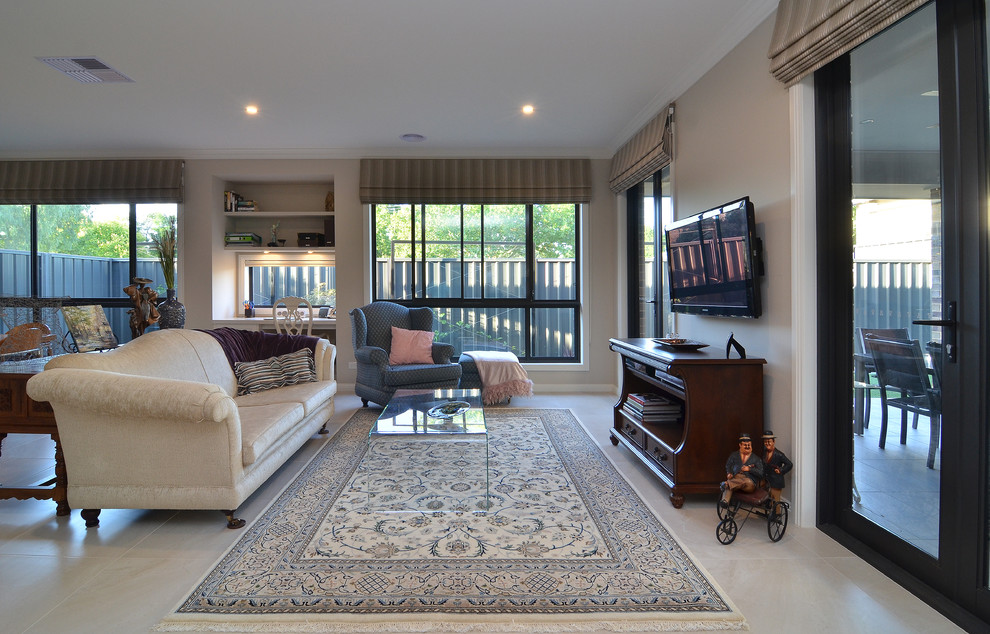 Modelo de sala de estar abierta clásica de tamaño medio con paredes beige, suelo de baldosas de cerámica y televisor colgado en la pared