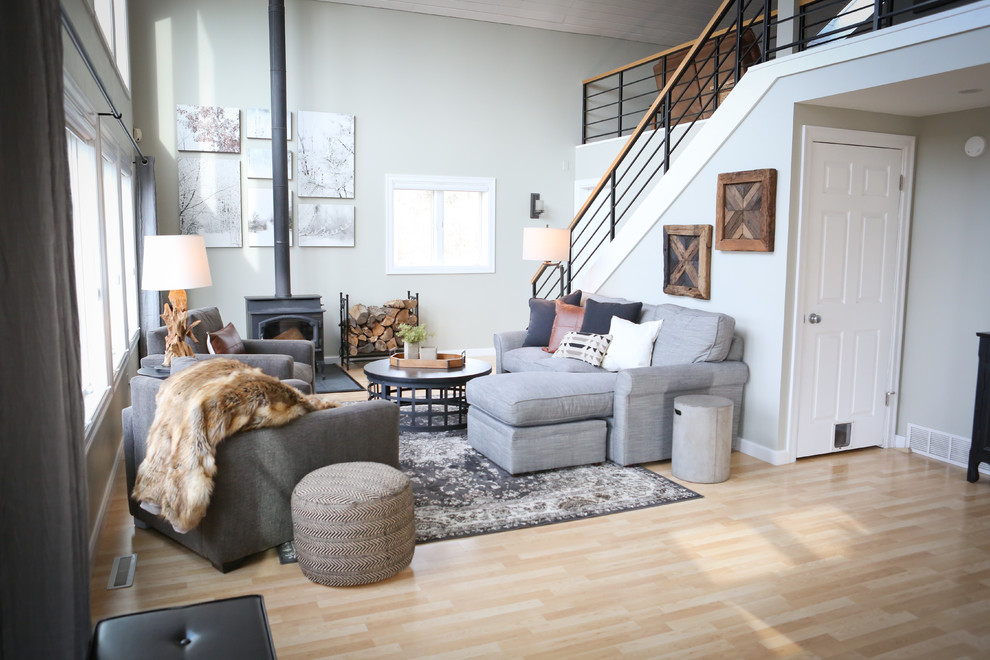 Ejemplo de sala de estar abierta tradicional renovada de tamaño medio sin televisor con paredes grises, suelo de madera clara, estufa de leña y marco de chimenea de metal