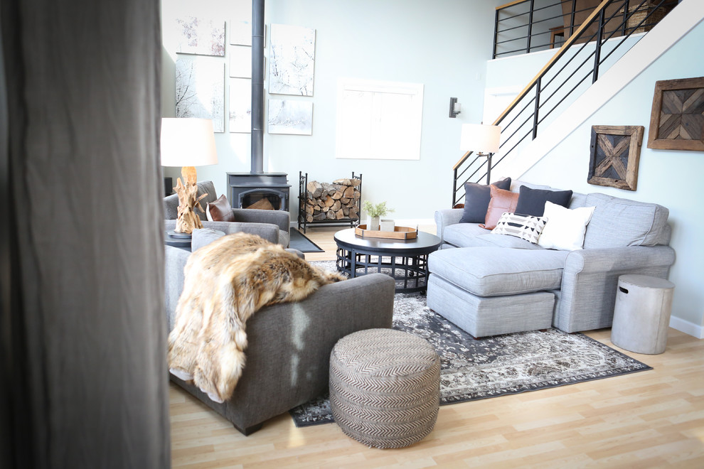 Diseño de sala de estar abierta clásica renovada de tamaño medio sin televisor con paredes grises, suelo de madera clara, estufa de leña y marco de chimenea de metal