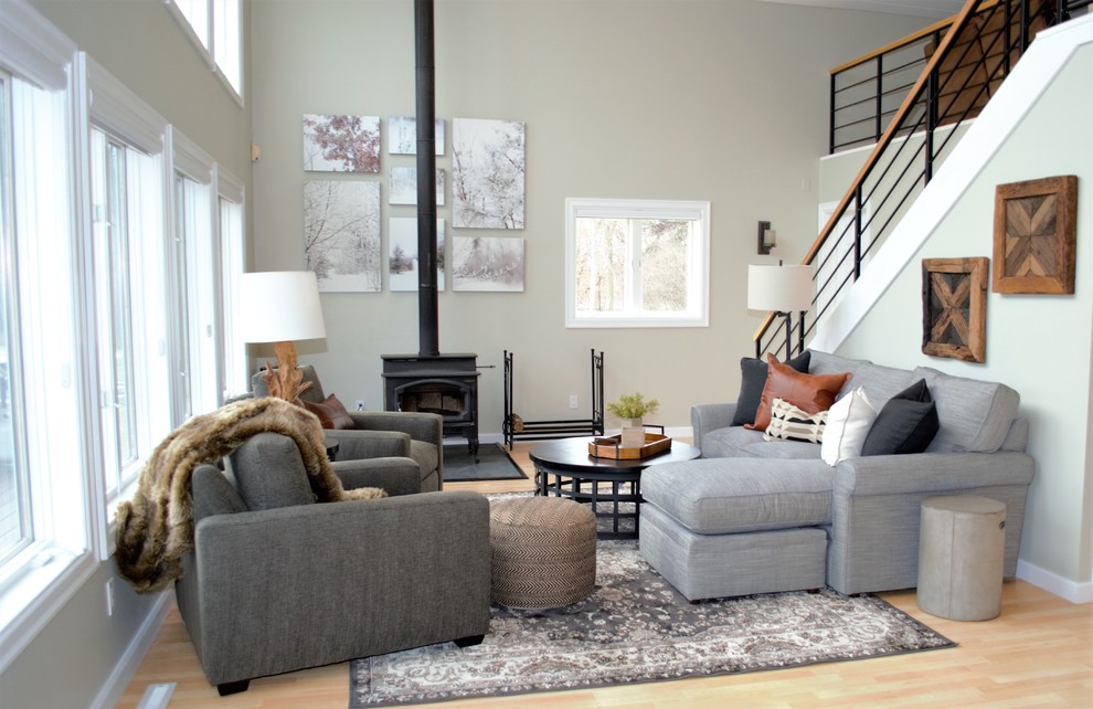 Foto de sala de estar abierta clásica renovada de tamaño medio sin televisor con paredes grises, suelo de madera clara, estufa de leña y marco de chimenea de metal
