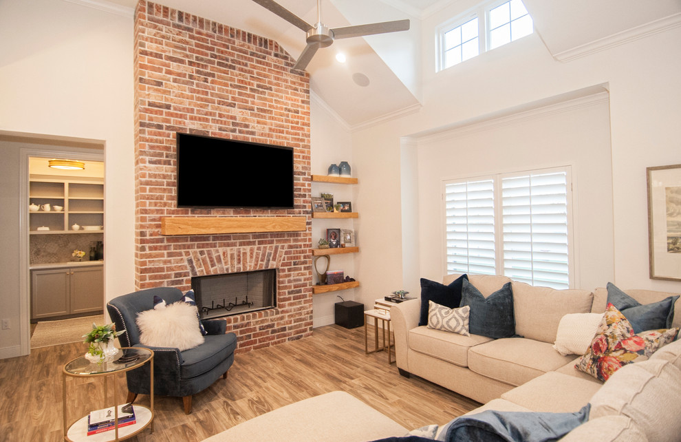 Medium sized farmhouse open plan games room in Austin with white walls, medium hardwood flooring, a standard fireplace, a brick fireplace surround, a wall mounted tv and grey floors.