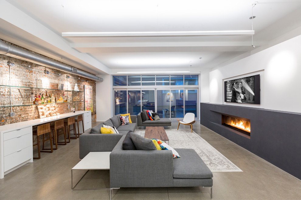 This is an example of an industrial games room in Cincinnati with white walls, concrete flooring, a ribbon fireplace, a wall mounted tv and grey floors.