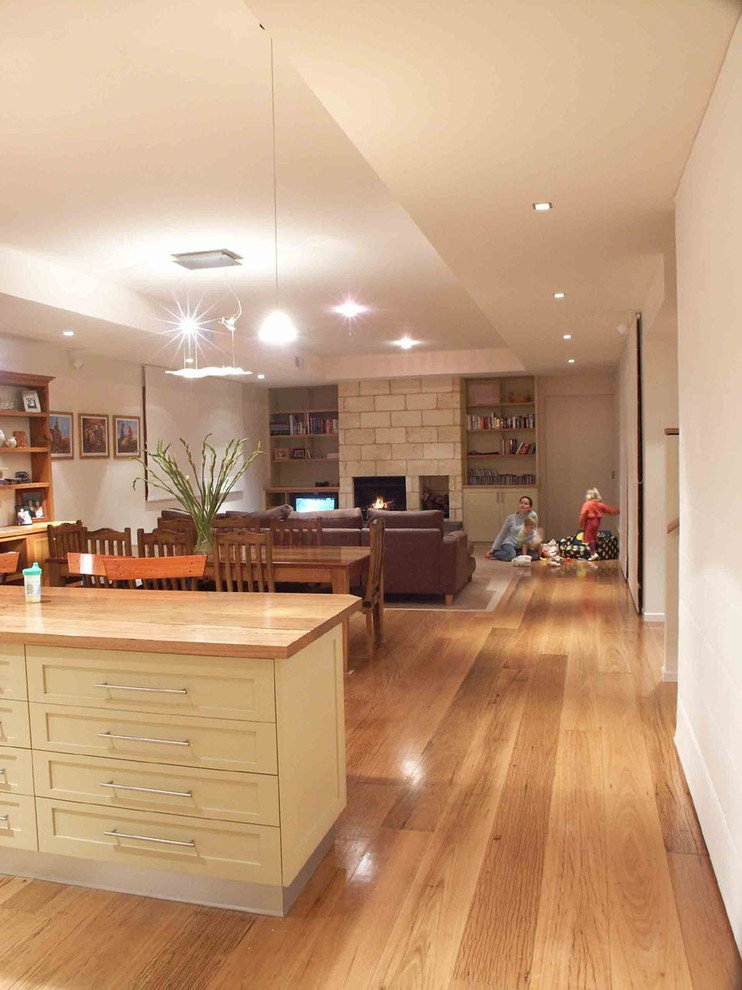 Diseño de sala de estar abierta contemporánea pequeña con paredes beige, suelo de madera clara, todas las chimeneas, marco de chimenea de ladrillo y pared multimedia