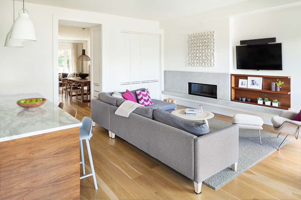 Mittelgroßes, Offenes Modernes Wohnzimmer mit weißer Wandfarbe, hellem Holzboden, Gaskamin, Kaminumrandung aus Stein und TV-Wand in Vancouver