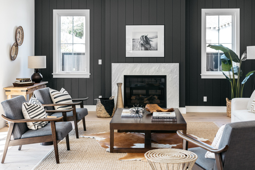 Ejemplo de sala de estar abierta de estilo de casa de campo con paredes negras y suelo de madera clara