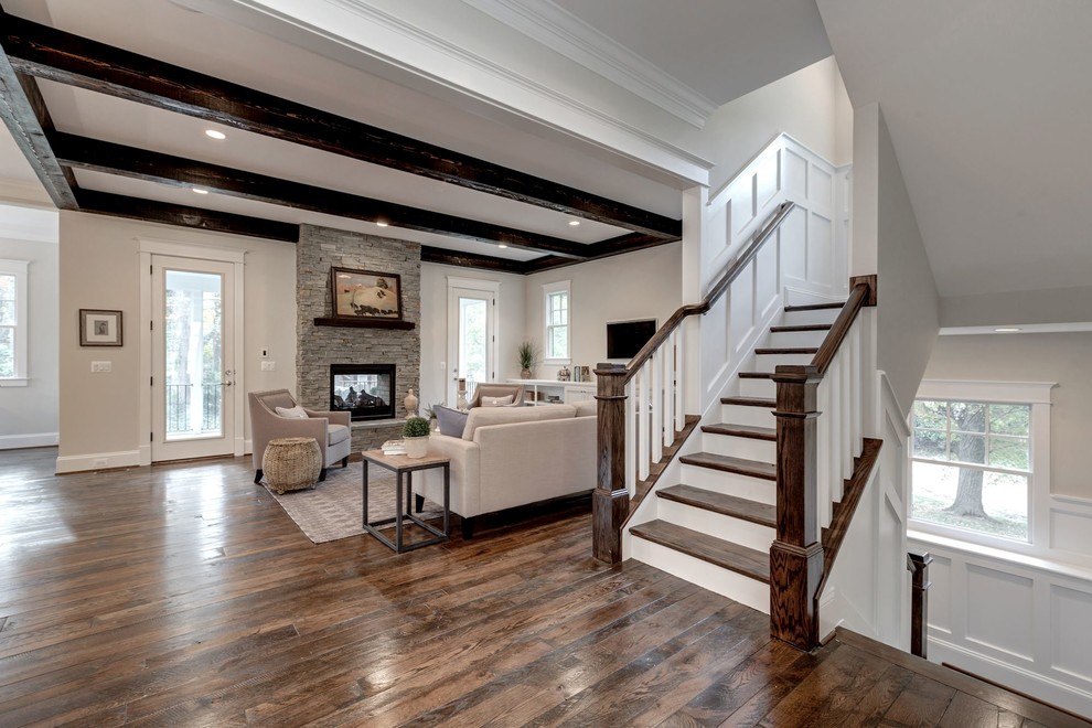 Large rural open plan games room in DC Metro with beige walls, dark hardwood flooring, a standard fireplace, a stone fireplace surround and a wall mounted tv.
