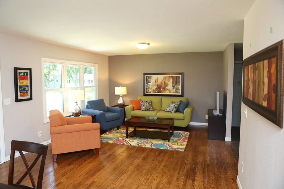 Cette photo montre une salle de séjour tendance de taille moyenne et ouverte avec un mur gris, un sol en bois brun, aucune cheminée et un téléviseur indépendant.