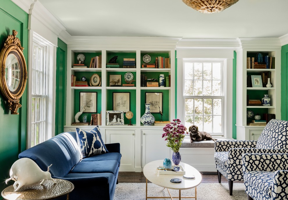 На фото: изолированная гостиная комната среднего размера в классическом стиле с с книжными шкафами и полками, зелеными стенами, паркетным полом среднего тона, стандартным камином, фасадом камина из камня, синим диваном и ковром на полу без телевизора