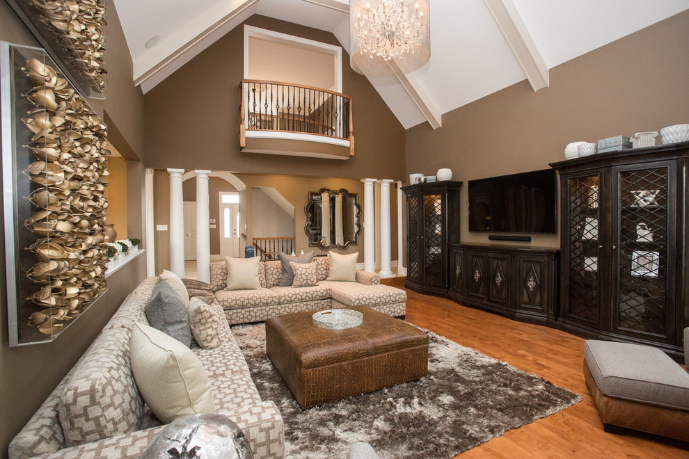 This is an example of a large classic open plan games room in Philadelphia with beige walls, medium hardwood flooring, a standard fireplace, a concrete fireplace surround, a wall mounted tv, brown floors and exposed beams.