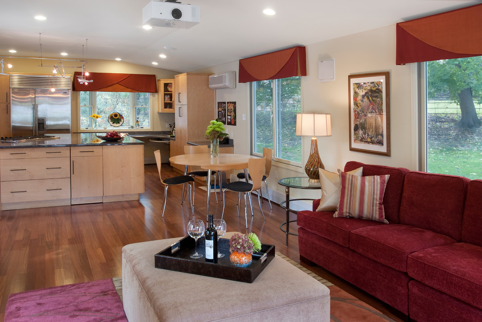Imagen de sala de estar abierta contemporánea extra grande sin chimenea con suelo de madera en tonos medios, paredes beige y televisor retractable