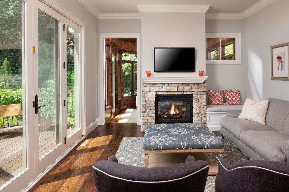Пример оригинального дизайна: гостиная комната в современном стиле с серыми стенами, паркетным полом среднего тона, стандартным камином, фасадом камина из камня и телевизором на стене