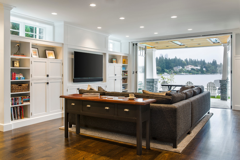 Imagen de sala de estar abierta tradicional renovada de tamaño medio sin chimenea con paredes blancas, suelo de madera oscura, televisor colgado en la pared y suelo marrón