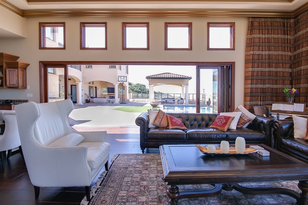 Imagen de sala de estar abierta mediterránea grande sin televisor con paredes blancas, suelo de madera oscura, chimenea lineal y marco de chimenea de yeso