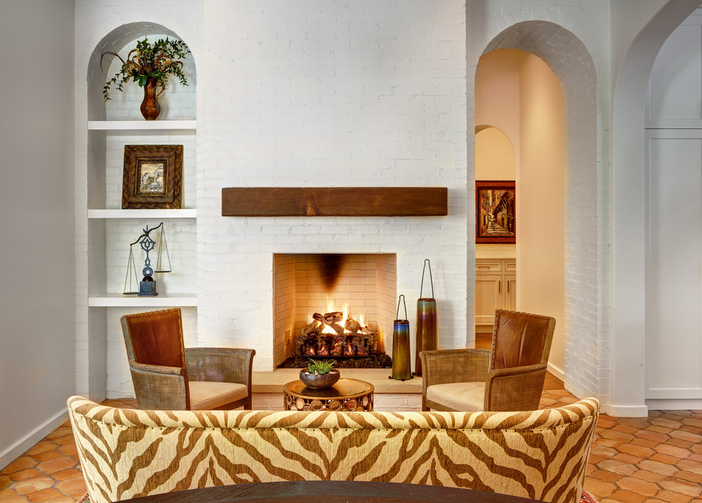 Inspiration pour une salle de séjour méditerranéenne de taille moyenne avec un mur blanc, tomettes au sol, une cheminée standard et un manteau de cheminée en brique.