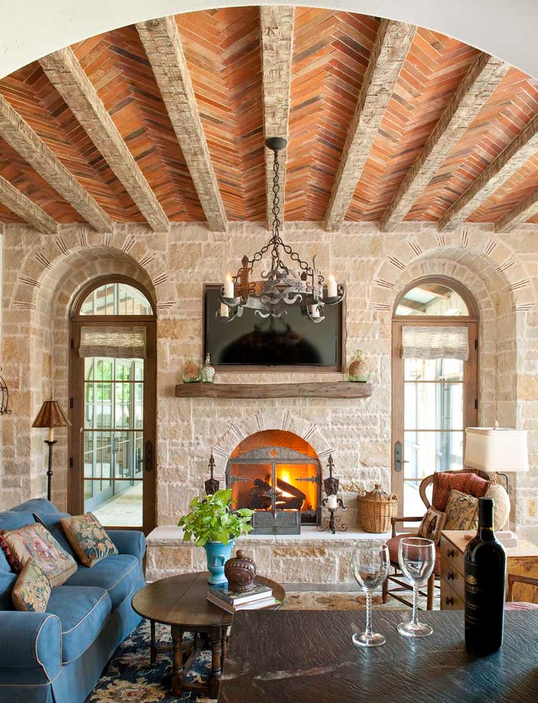 Modelo de sala de estar mediterránea con todas las chimeneas, marco de chimenea de piedra y televisor colgado en la pared
