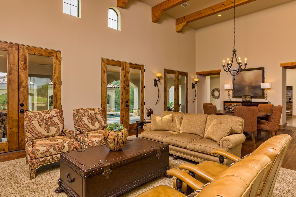 Großes, Offenes Mediterranes Wohnzimmer mit beiger Wandfarbe, braunem Holzboden, Kamin, Kaminumrandung aus Stein und TV-Wand in Austin