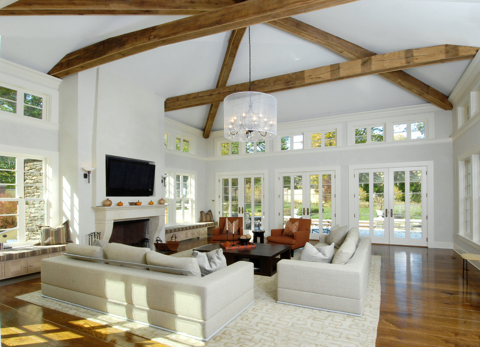 Diseño de sala de estar abierta mediterránea con paredes grises, suelo de madera en tonos medios, todas las chimeneas y televisor colgado en la pared