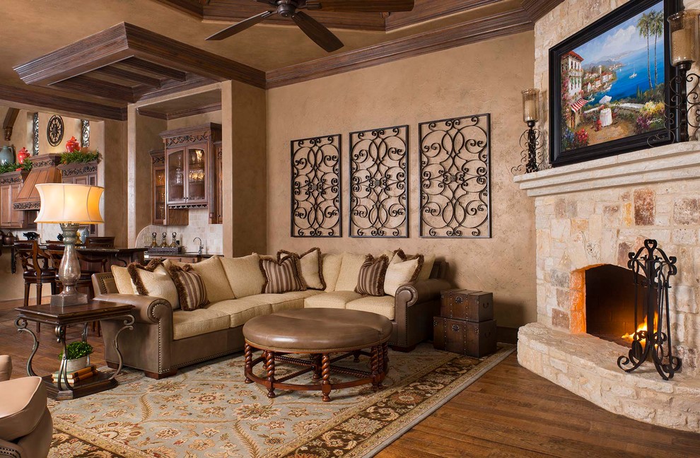 Foto de sala de estar abierta mediterránea grande con paredes beige, suelo de madera en tonos medios, todas las chimeneas y marco de chimenea de piedra