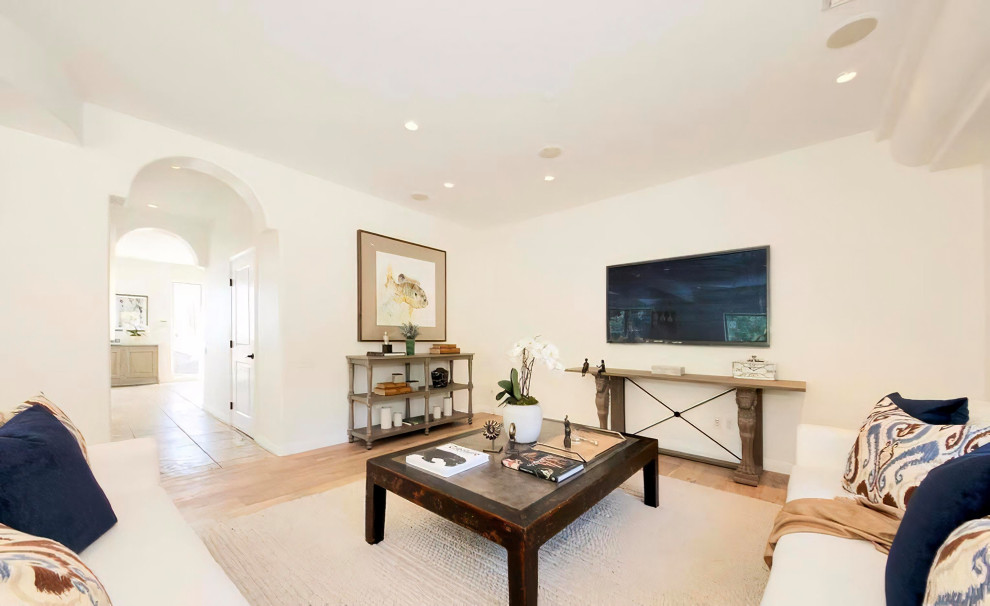 Großes, Offenes Mediterranes Wohnzimmer ohne Kamin mit weißer Wandfarbe, hellem Holzboden, TV-Wand und beigem Boden in Los Angeles