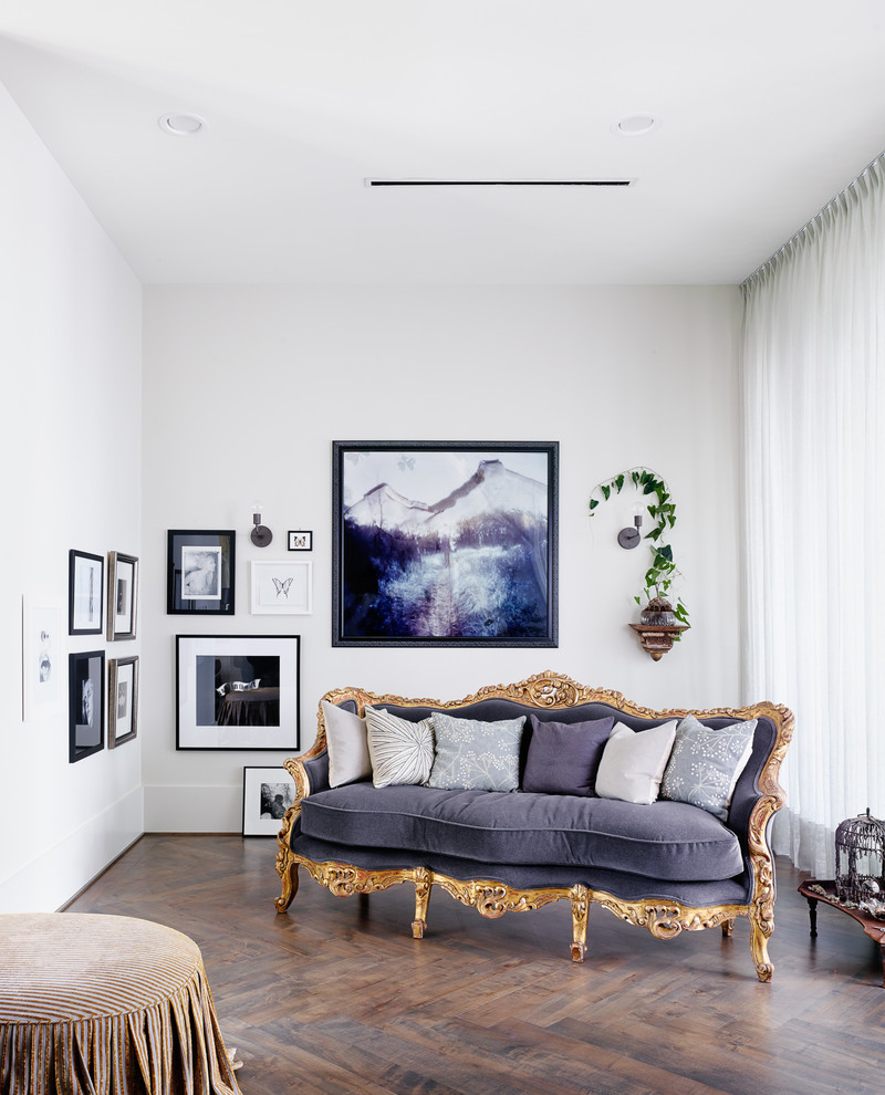 Modelo de sala de estar bohemia sin chimenea y televisor con paredes blancas y suelo de madera oscura