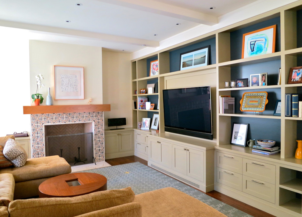 Imagen de sala de estar tradicional con paredes beige, todas las chimeneas, marco de chimenea de baldosas y/o azulejos y televisor colgado en la pared
