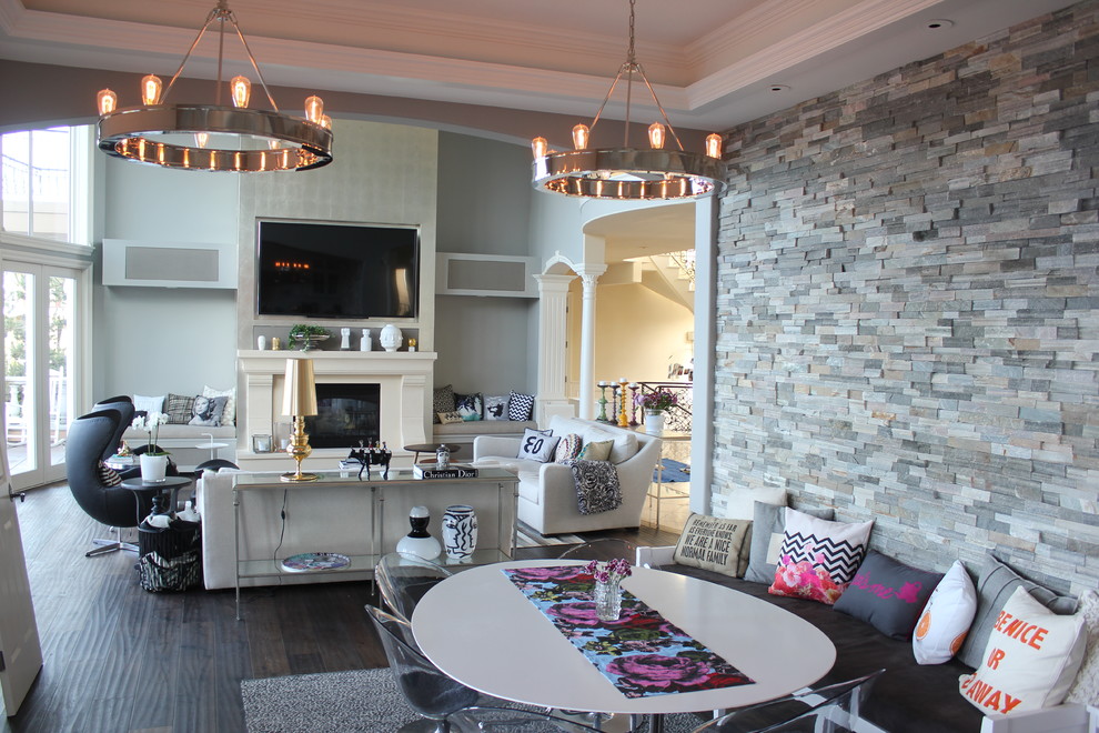 Foto de sala de estar moderna grande con paredes grises, suelo de madera oscura, todas las chimeneas, marco de chimenea de piedra y pared multimedia