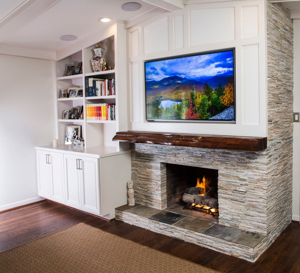 Modelo de sala de estar abierta tradicional renovada de tamaño medio con paredes grises, suelo de madera en tonos medios, todas las chimeneas, marco de chimenea de piedra y pared multimedia
