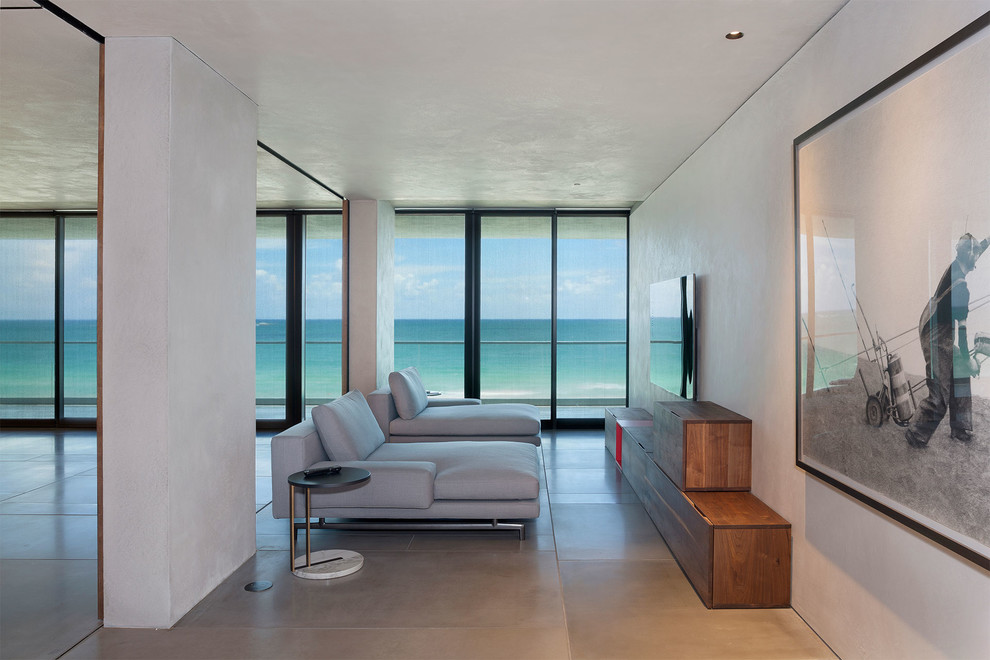 Example of a mid-sized trendy enclosed porcelain tile and beige floor family room design in Miami with white walls and a wall-mounted tv