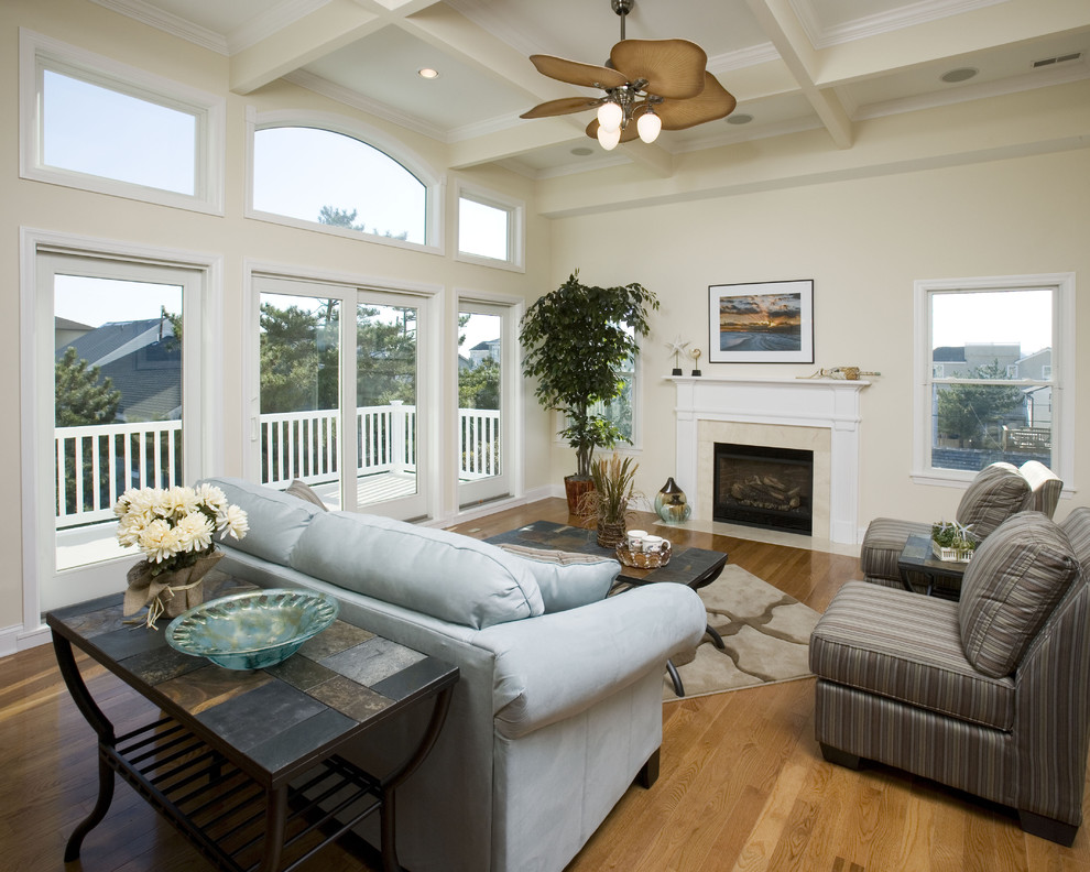 Imagen de sala de estar abierta clásica de tamaño medio con paredes beige, suelo de madera clara, todas las chimeneas y marco de chimenea de madera