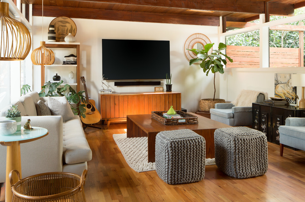 Ejemplo de sala de estar retro con paredes blancas, suelo de madera en tonos medios, televisor colgado en la pared y alfombra