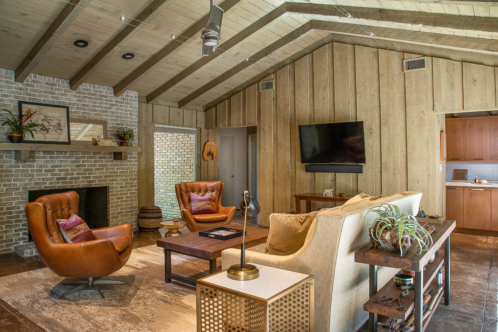 Cette photo montre une petite salle de séjour rétro fermée avec une cheminée standard, un manteau de cheminée en brique, un téléviseur fixé au mur, un sol marron, un mur gris et sol en béton ciré.