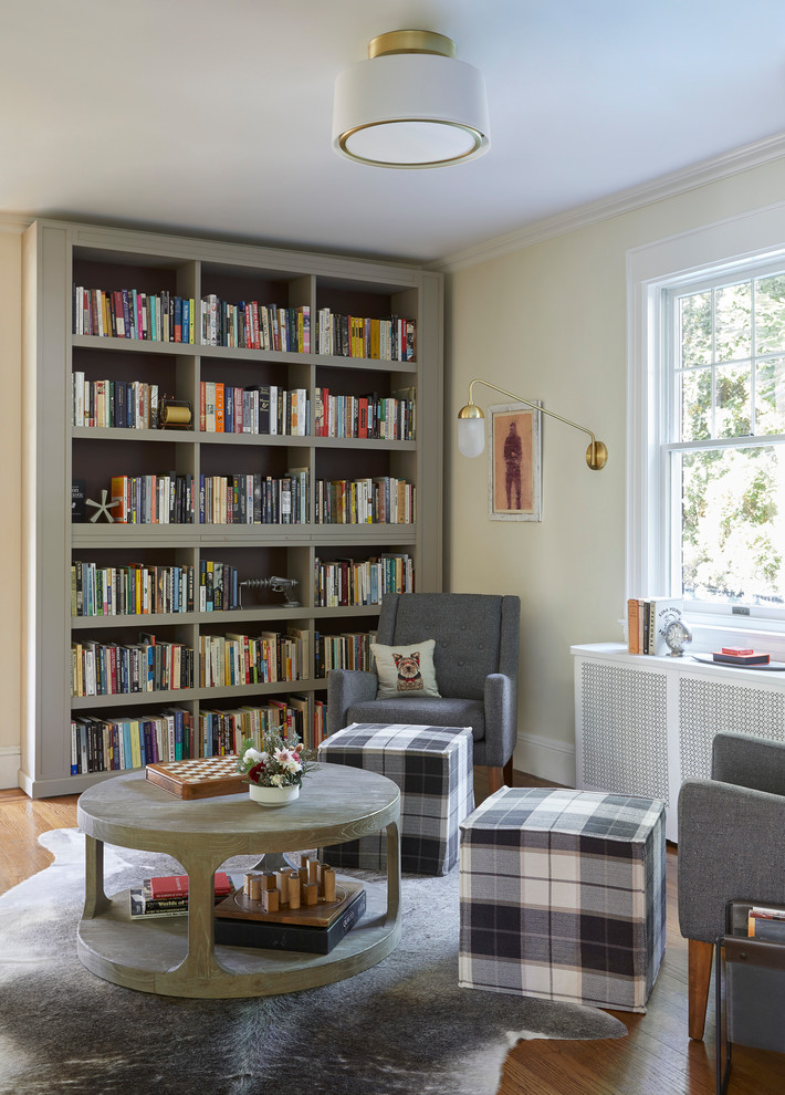 Foto de sala de estar con biblioteca abierta clásica renovada de tamaño medio sin chimenea y televisor con paredes beige, suelo de madera en tonos medios, suelo marrón y alfombra