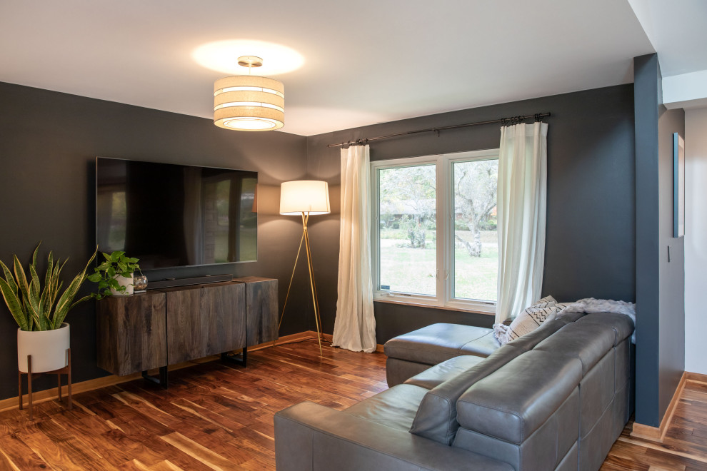 Foto di un soggiorno moderno di medie dimensioni e aperto con pareti nere, pavimento in legno massello medio, TV a parete e pavimento marrone
