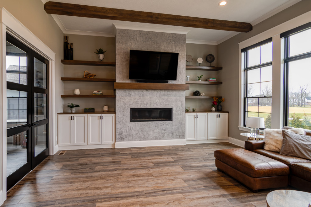 Mittelgroßes, Offenes Mid-Century Wohnzimmer mit grauer Wandfarbe, braunem Holzboden, Kamin, verputzter Kaminumrandung, TV-Wand und braunem Boden in Indianapolis