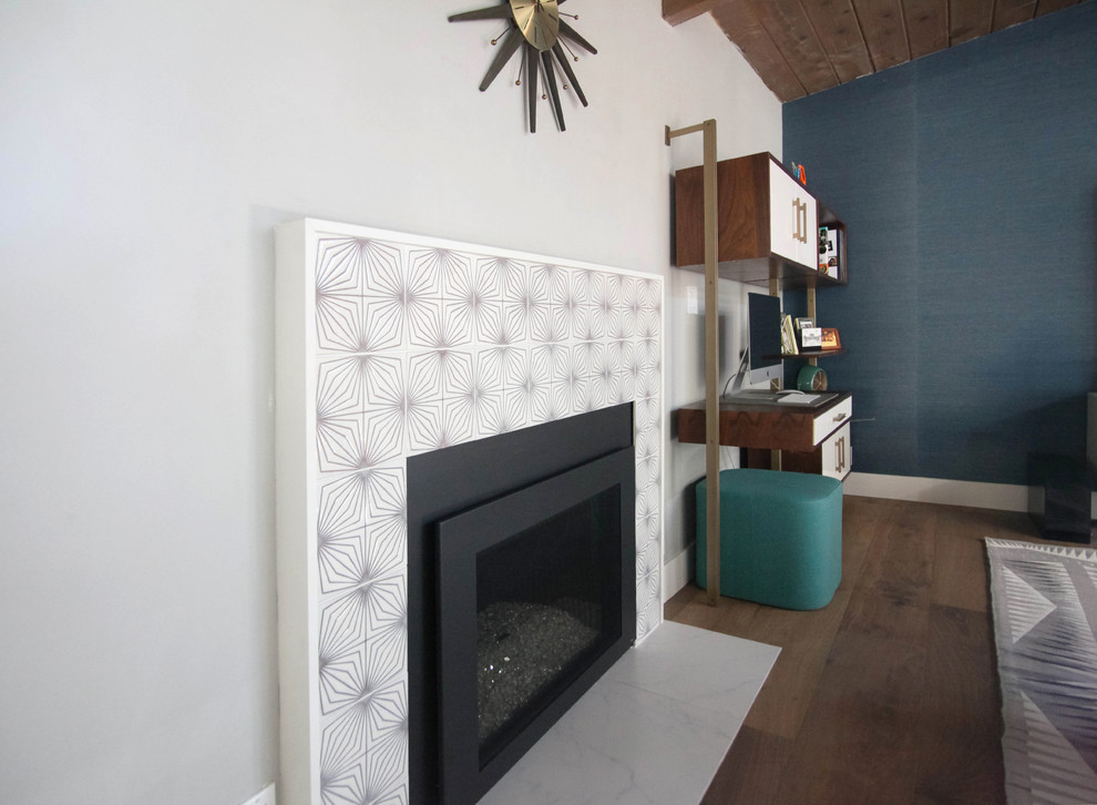 Photo of a midcentury games room in San Francisco with blue walls, medium hardwood flooring, a standard fireplace, a tiled fireplace surround, a freestanding tv and brown floors.
