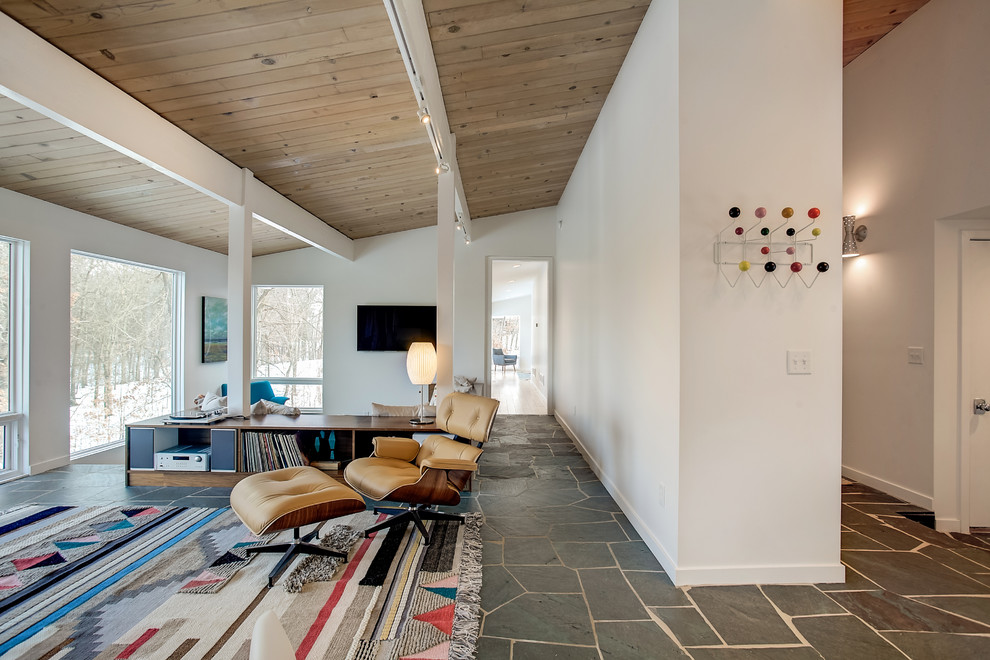 Immagine di un soggiorno minimalista di medie dimensioni e aperto con pareti bianche, pavimento in ardesia, TV a parete, nessun camino e pavimento grigio