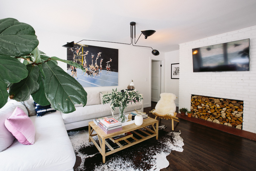 Свежая идея для дизайна: изолированная гостиная комната в стиле неоклассика (современная классика) с белыми стенами, темным паркетным полом, телевизором на стене, стандартным камином, фасадом камина из кирпича и коричневым полом - отличное фото интерьера