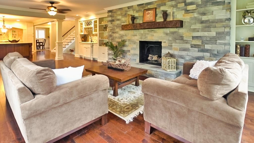 Inspiration pour une grande salle de séjour vintage ouverte avec un mur gris, parquet foncé, une cheminée standard, un manteau de cheminée en pierre et un sol marron.