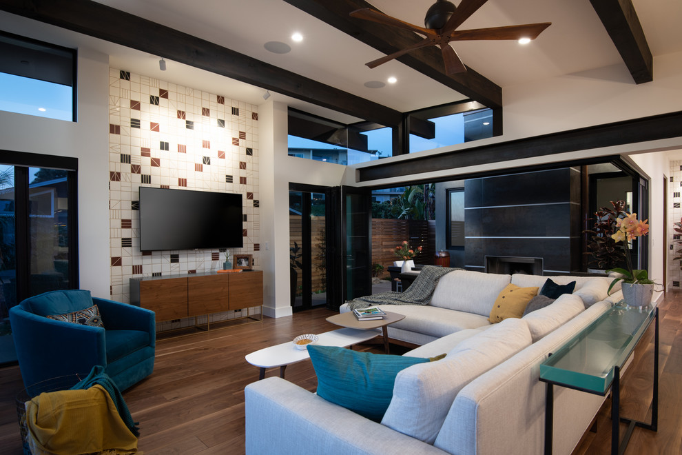 Cette photo montre un salon rétro de taille moyenne et ouvert avec un sol en bois brun, un téléviseur fixé au mur, un mur blanc, une cheminée standard et un sol marron.