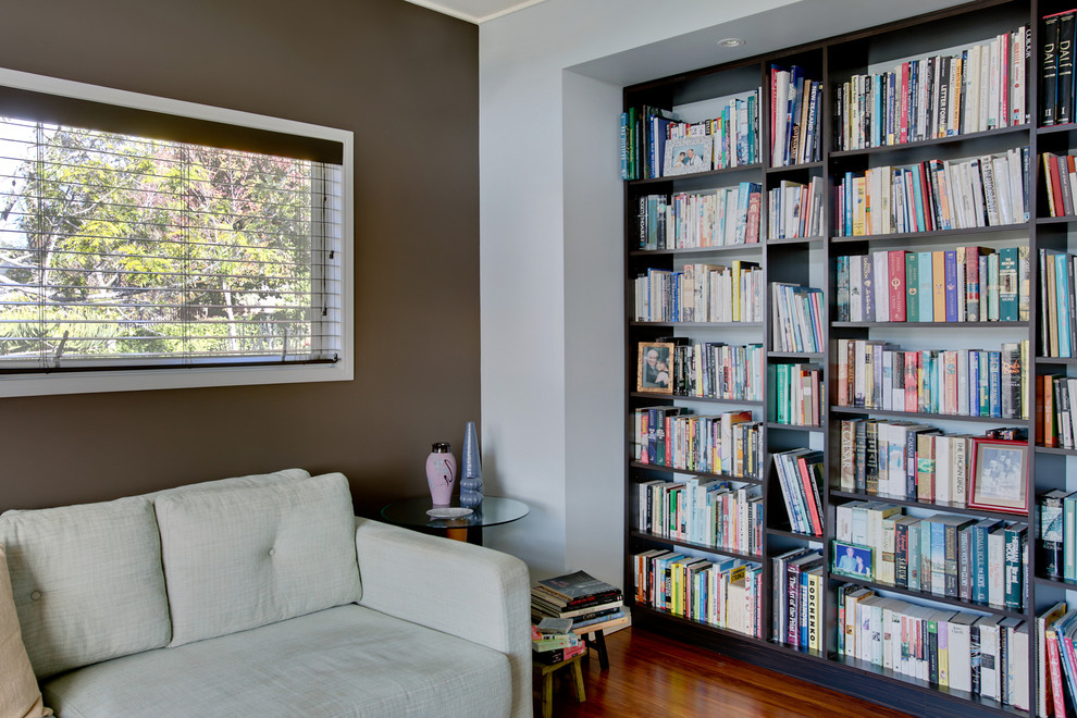 Modelo de sala de estar con biblioteca cerrada actual de tamaño medio con paredes azules, suelo de madera en tonos medios y televisor independiente