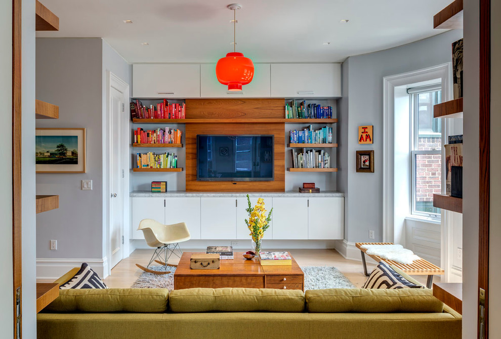 На фото: изолированная гостиная комната среднего размера в стиле ретро с с книжными шкафами и полками, серыми стенами, светлым паркетным полом и телевизором на стене без камина с