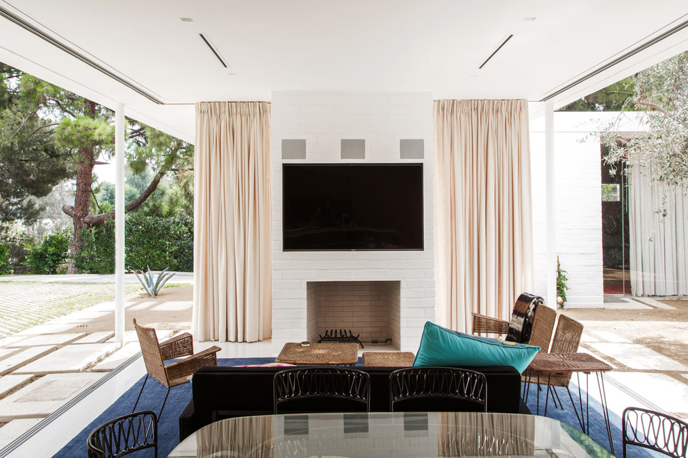 Immagine di un soggiorno minimalista aperto con camino classico e TV a parete