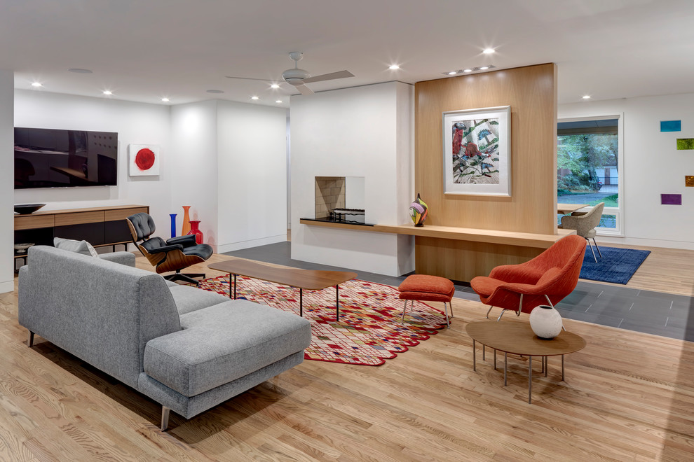 Diseño de sala de estar vintage con paredes blancas, suelo de madera clara, chimenea de doble cara, televisor colgado en la pared y suelo beige