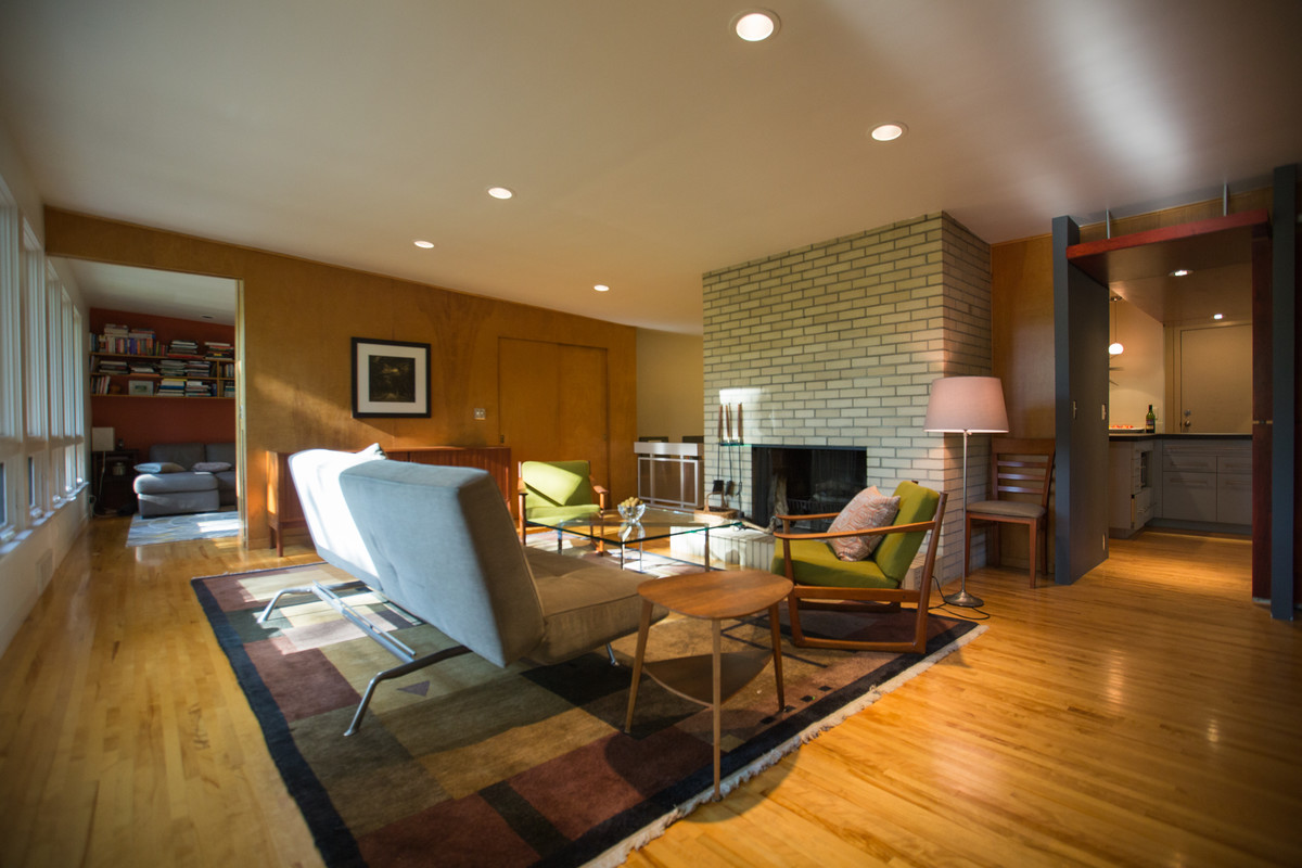 Photo of a retro open plan games room in Minneapolis with multi-coloured walls, light hardwood flooring, a standard fireplace, a brick fireplace surround and brown floors.