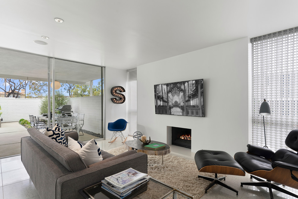 Diseño de sala de estar abierta retro con paredes blancas, todas las chimeneas, televisor colgado en la pared y suelo gris
