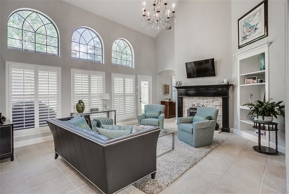 This is an example of a large classic open plan games room in Dallas with grey walls, ceramic flooring, a standard fireplace, a stone fireplace surround, a wall mounted tv and beige floors.